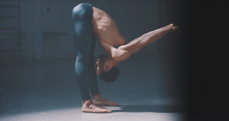 A guy performing a challenging yoga exercise, pushing himself to his limits